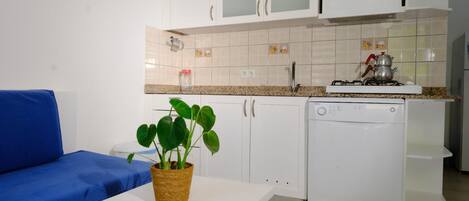 A compact kitchen with white cabinets, a gas stove, and a dishwasher.