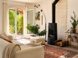 Un salon comprenant un canapé, une table basse, une cheminée, une bibliothèque et une vue sur la verdure à l’extérieur.