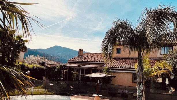 A swimming pool with a clear view of the surrounding area, including a building with a tiled roof and a mountain in the background. - Villa with all comforts, ideal for families or friends: swimming pool, ps5, paddles (Solliès-Pont)