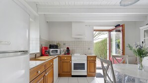 Une cuisine avec des meubles blancs, un four à micro-ondes, une machine à café et un four traditionnel.