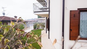 Ein Wohngebäude mit Balkon, Garten und Blick auf Nachbarhäuser.