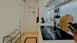 A modern kitchen with a black stove, white cabinets, and a wooden cutting board. - Luxury Wimbledon 2B2B | Cinema • Gym • Games Room (London)