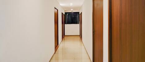 A long, narrow hallway with wooden doors on both sides and a tiled floor.