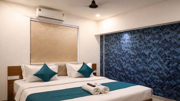 Una camera d'albergo con un letto, una finestra, un condizionatore e una parete decorata.