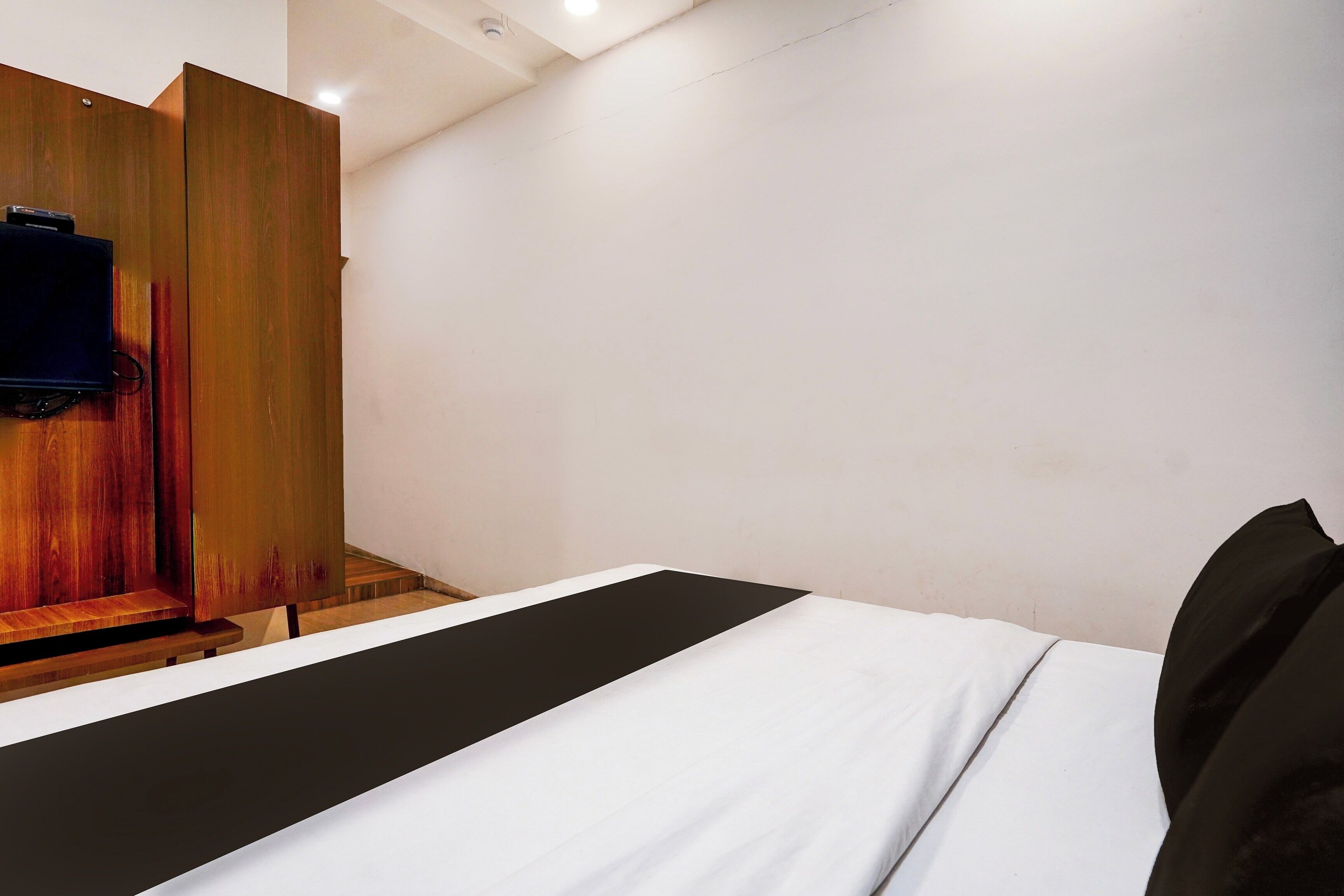 A hotel room with a bed, a wooden wardrobe, and a television.