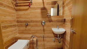 Un bagno con rivestimenti in legno, un water, un lavandino, una doccia e un porta asciugamani.