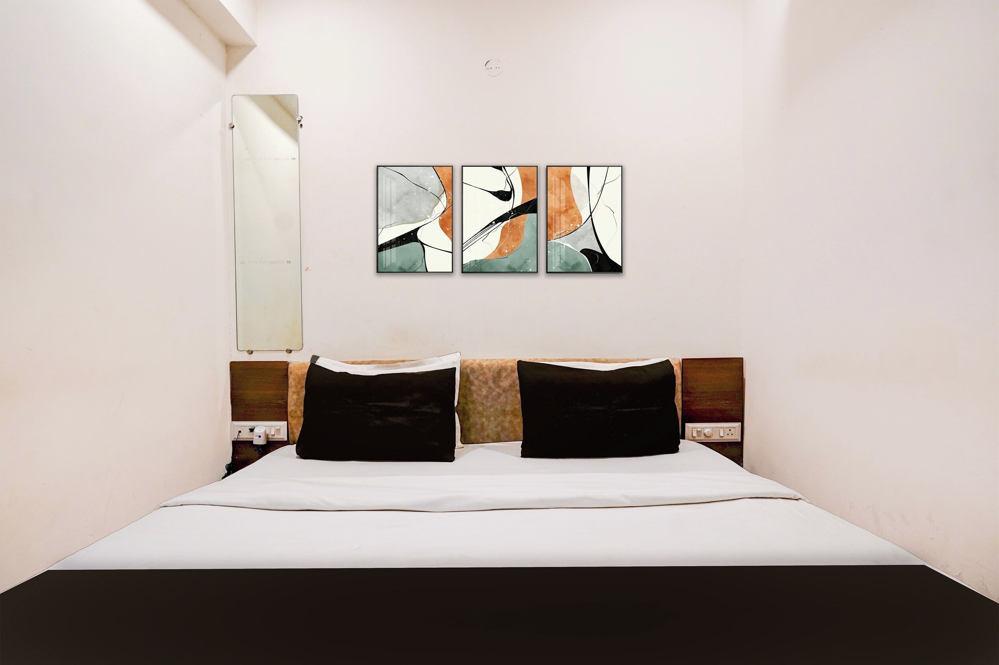Una habitación de hotel con cama, espejo en la pared y arte abstracto.