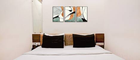 Una habitación de hotel con cama, espejo en la pared y arte abstracto.