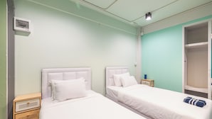 A room with two beds, a wardrobe, and a small wooden nightstand. - Queen On Street Guesthouse (Phuket)