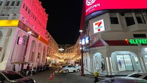 A street view at night with a 7-Eleven store and a building with a red awning. - Queen On Street Guesthouse (Phuket)