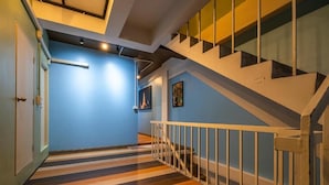A staircase with a white railing and a striped floor leading to a landing. - Queen On Street Guesthouse (Phuket)