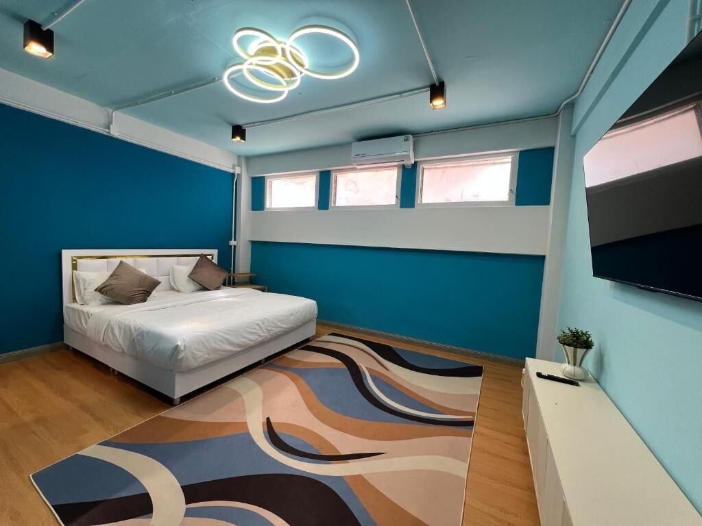 Quarto com uma cama, televisão, janela e luminária no teto.