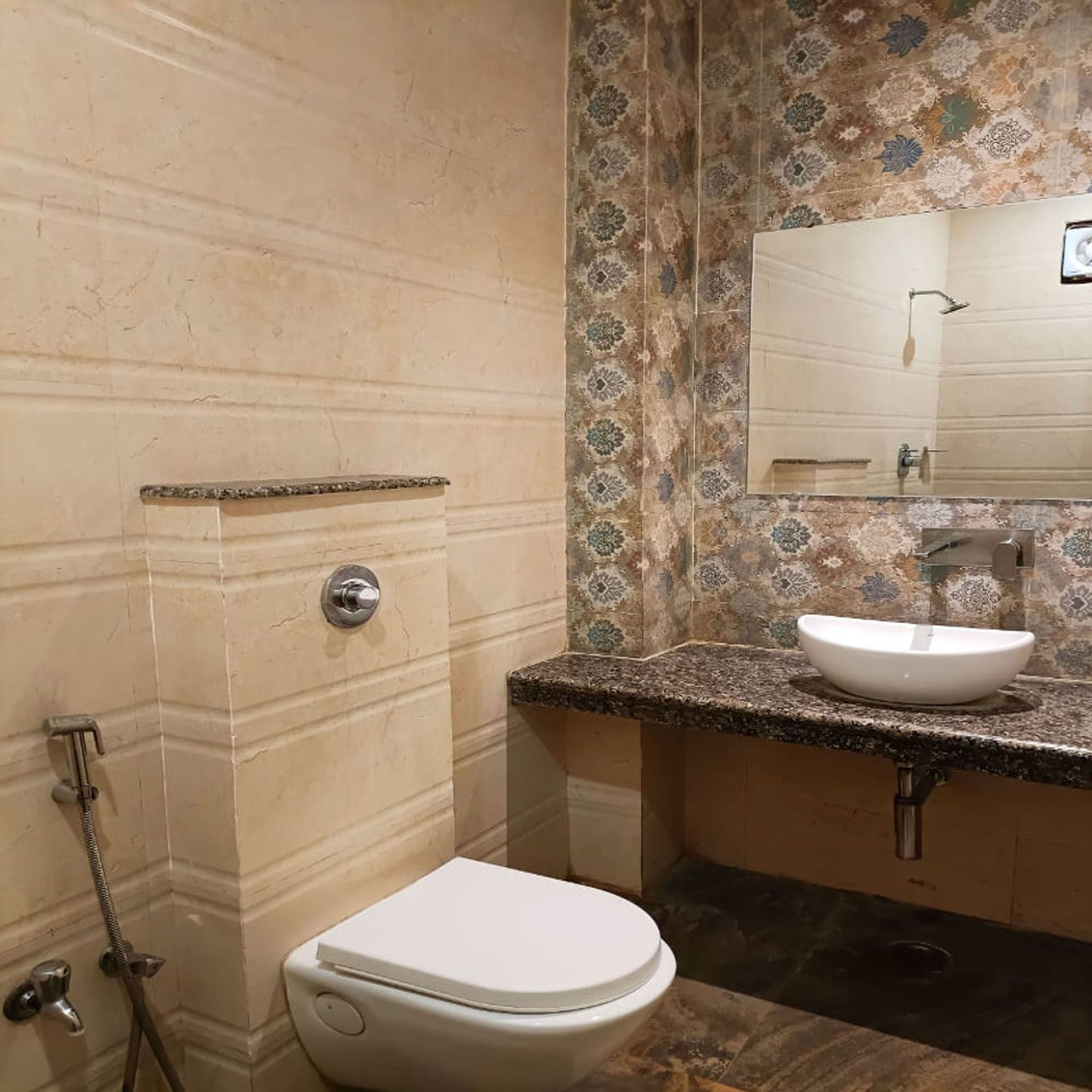 A bathroom with a toilet, sink, shower, and a mirror.