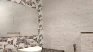 A bathroom with a white sink, a mirror, and a shower. - HOTEL NEEL GAGAN  (Varanasi)