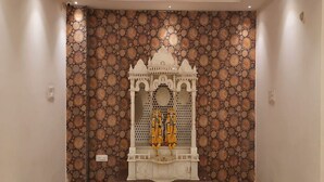 A hallway with a decorative alcove featuring a statue, a patterned wall, and a ceiling with recessed lighting. - HOTEL NEEL GAGAN  (Varanasi)