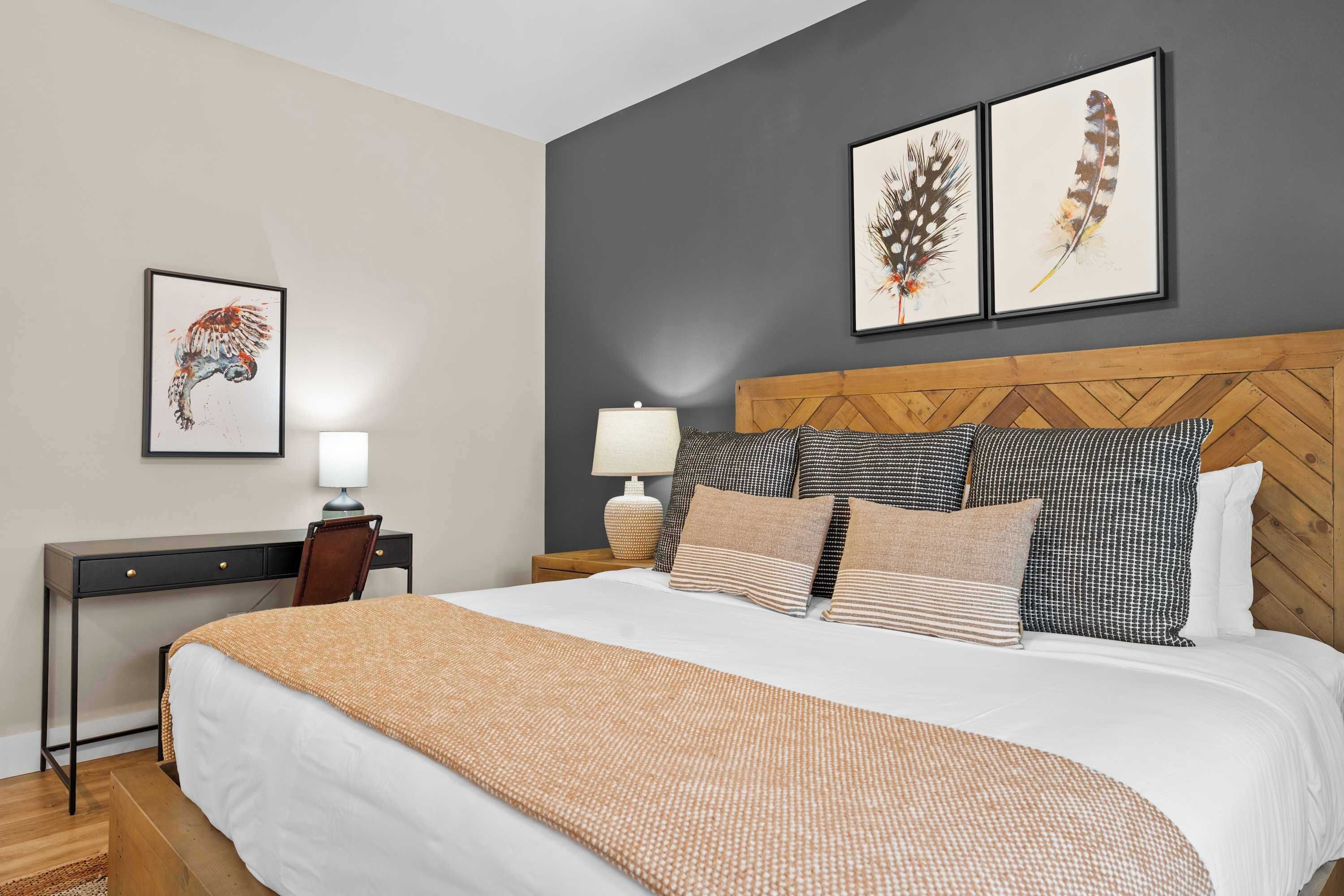 Ein Schlafzimmer mit einem Bett, einem Schreibtisch und zwei an der Wand befestigten Federbildern.