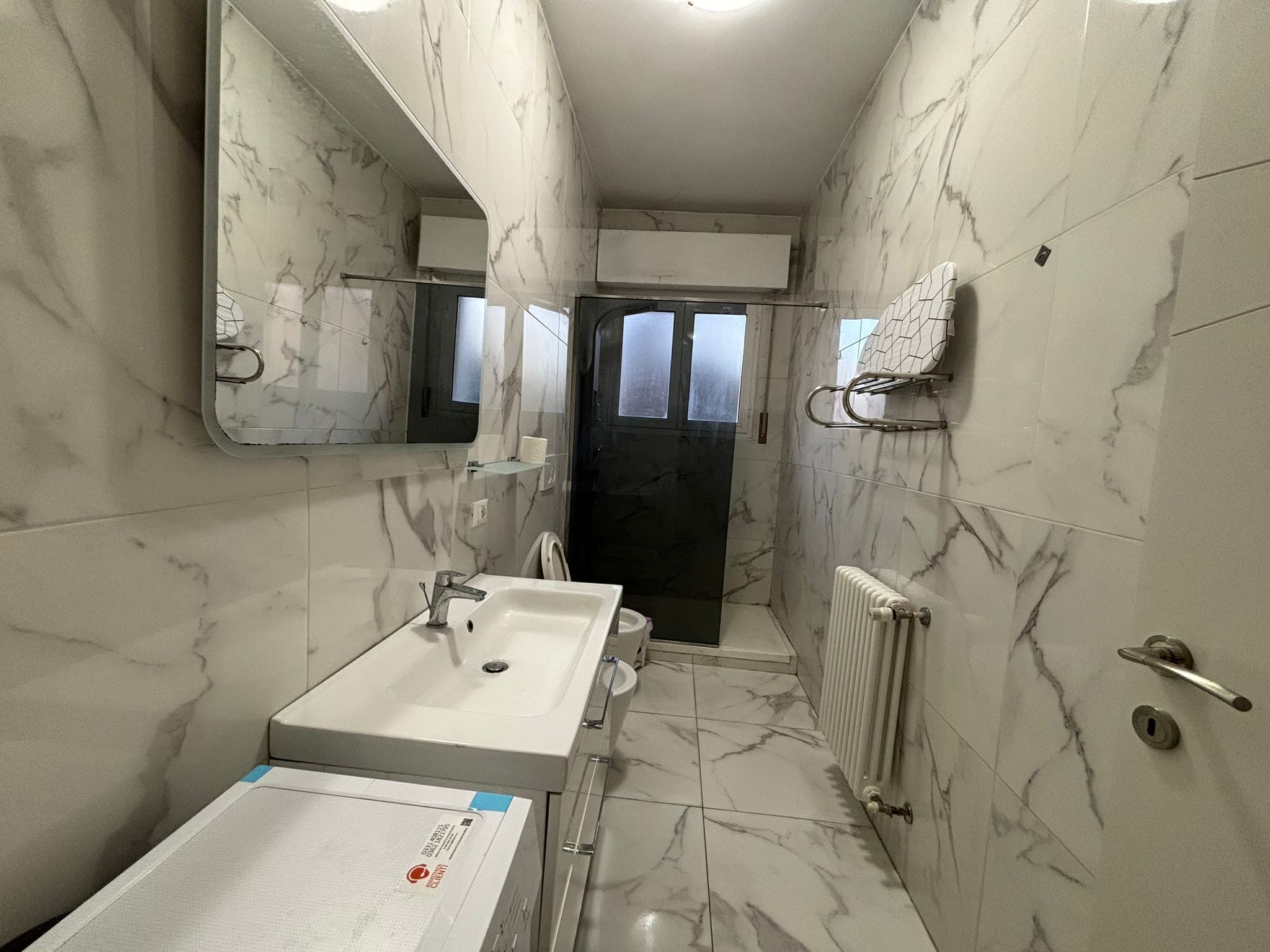 Une salle de bain avec un lavabo blanc, un miroir et un porte-serviettes.
