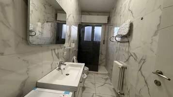 Une salle de bain avec un lavabo blanc, un miroir et un porte-serviettes.