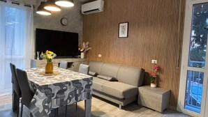 Ein modernes Wohnzimmer mit Esstisch, Sofa und Fernseher.