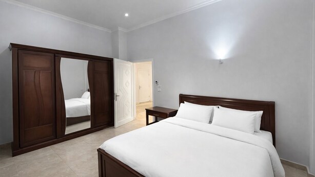Une chambre à coucher avec un grand lit, une armoire et un miroir.