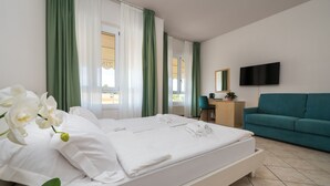 A hotel room with a bed, a desk, a chair, a sofa, a TV, and a window with curtains. - HOTEL MAX  LAZISE (Lazise)