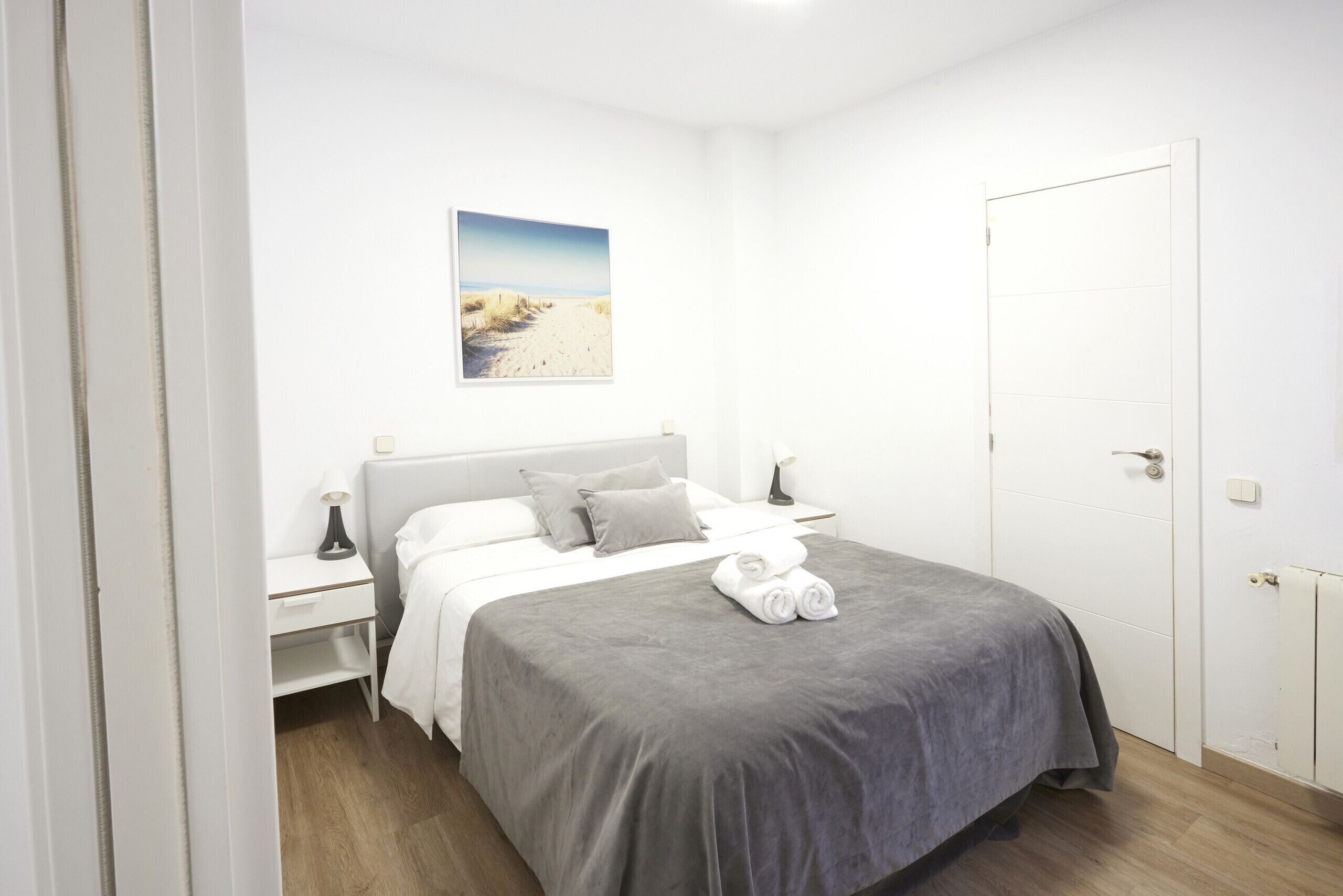 Una camera da letto con un letto, comodini, un quadro e una porta.