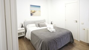 A bedroom with a bed, nightstands, a painting, and a door. - Santa Rosa Madrid 101 by Escape Home (Madrid)