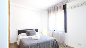 Un dormitorio con cama, cortinas y aire acondicionado.