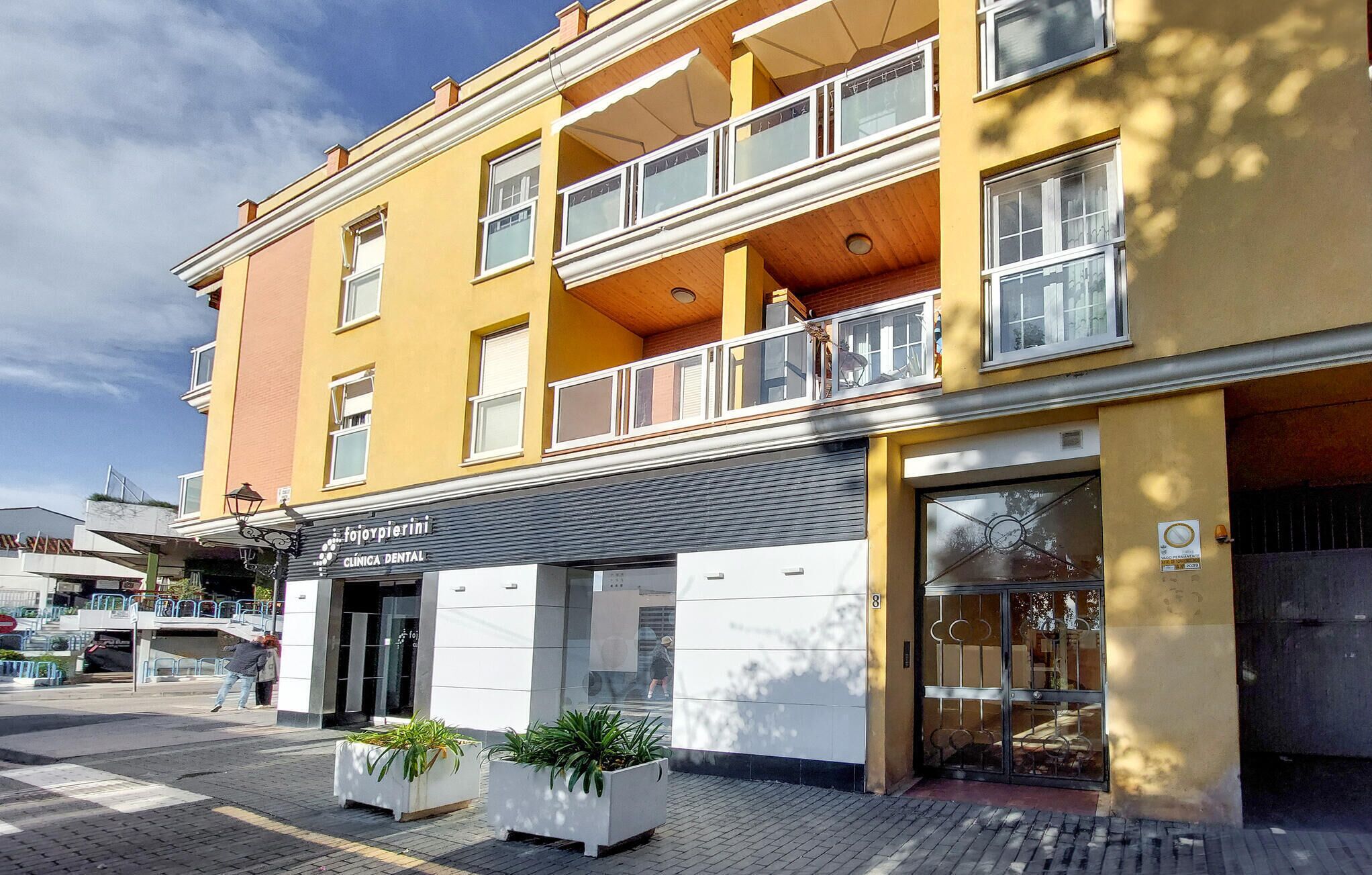 A multi-story building with a dental clinic on the ground floor, large windows, and a balcony.