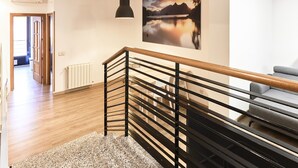 Un interno moderno con una scala in legno, vista su un lago e zona pranzo.