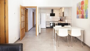 A modern kitchen with white cabinets, a dining table with chairs, and a colorful abstract painting on the wall. - Santa Rosa Madrid 204 by Escape Home (Madrid)