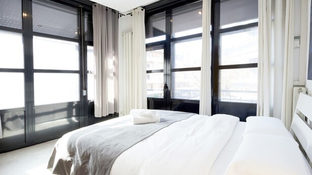 A modern hotel room with a large bed, a window with curtains, and a view of the city. - Santa Rosa Madrid 204 by Escape Home (Madrid)