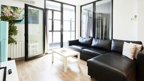 Ein modernes Wohnzimmer mit einer schwarzen Ledersofa, einem weißen Couchtisch und einer Glastür zu einem Außenbereich.