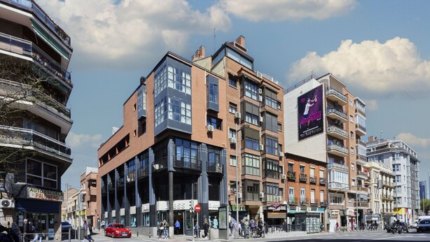Un edificio a più piani con spazi commerciali e residenziali, comprensivo di un negozio e balconi.