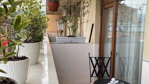 A balcony with potted plants, a table with a cushion, and a chair. - Siqvaruli (Tbilisi)