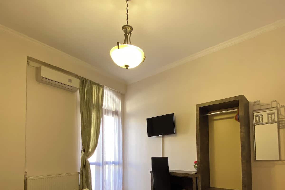 A hotel room with a bed, a desk, a TV, and a wardrobe.