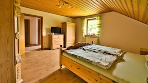 Ein Schlafzimmer aus Holz mit Bett, Schminktisch und Fernseher.