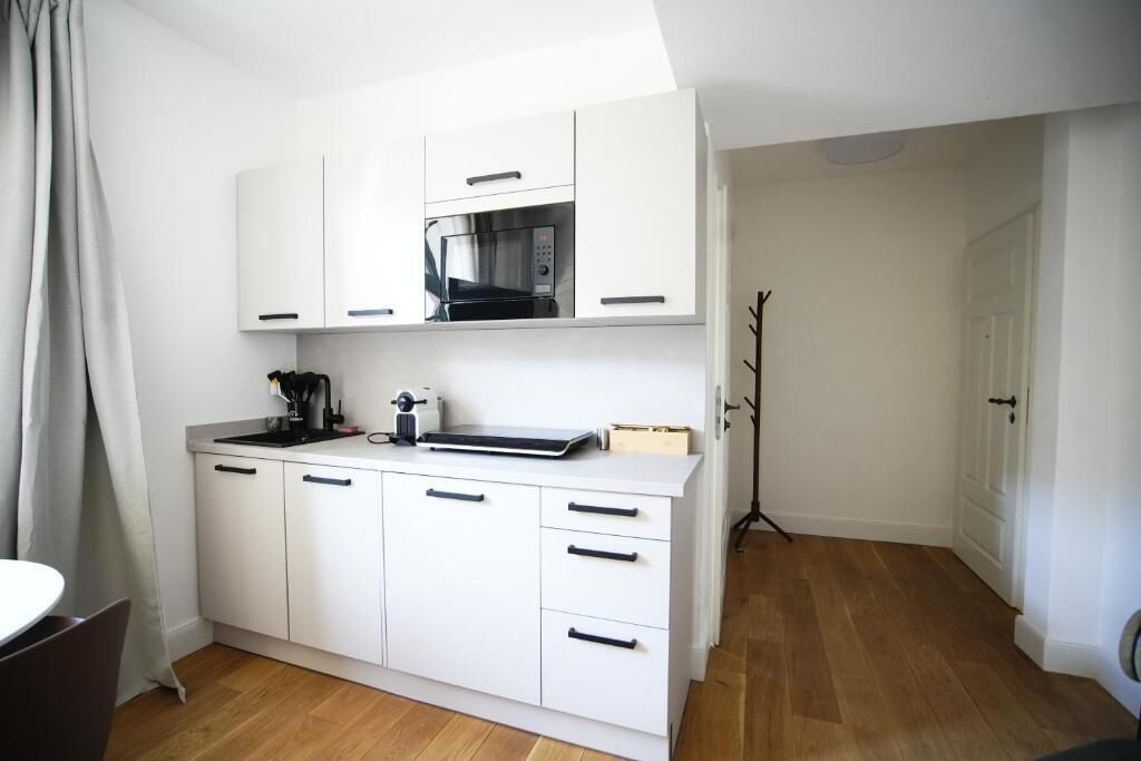 A compact kitchen with white cabinets, a microwave, and a coffee machine.
