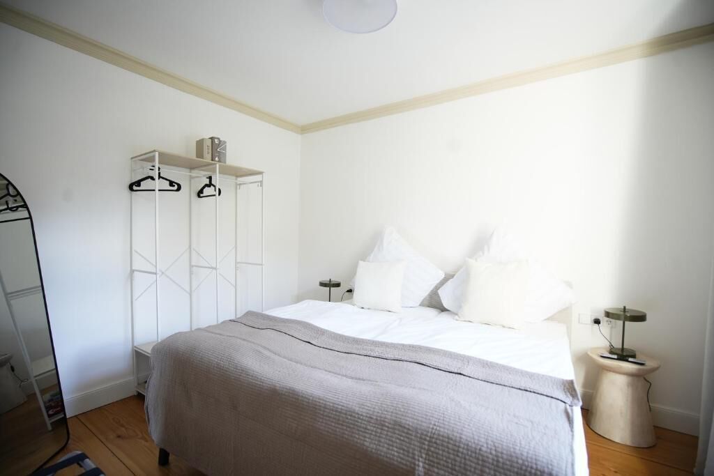 A bedroom with a bed, white wardrobe, and bedside tables.