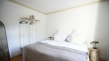 A bedroom with a bed, white wardrobe, and bedside tables.