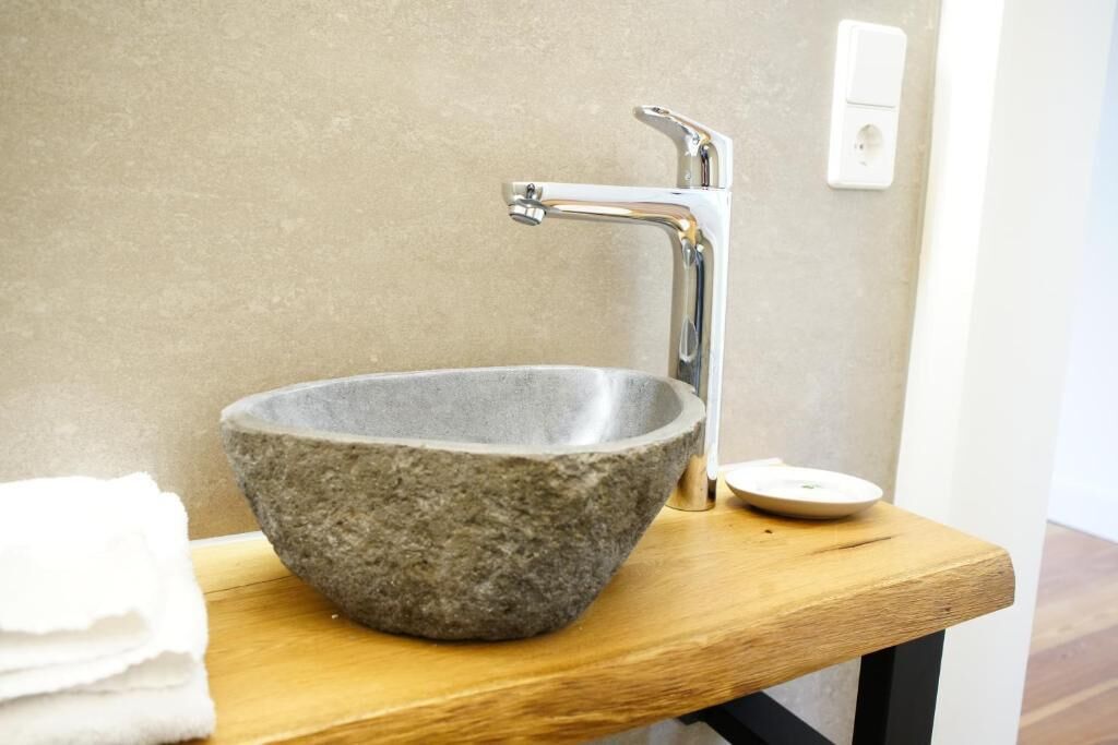 A stone basin sink with a modern faucet on a wooden countertop.