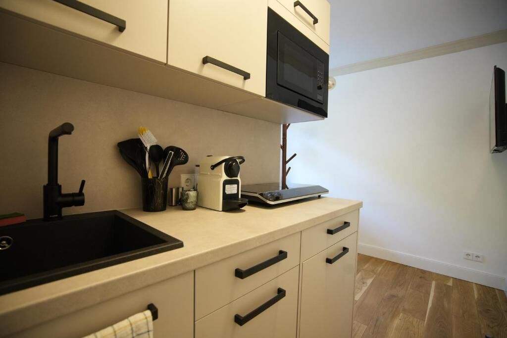 A kitchen with a black sink, a microwave, and a coffee maker on the countertop.