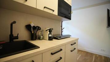 A kitchen with a black sink, a microwave, and a coffee maker on the countertop.