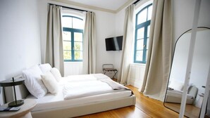 A bedroom with a bed, a TV, and a window with curtains. - Königsgleis-Apartments (Bad Wildbad)