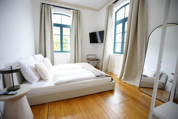 A bedroom with a bed, a TV, and a window with curtains. - Königsgleis-Apartments (Bad Wildbad)