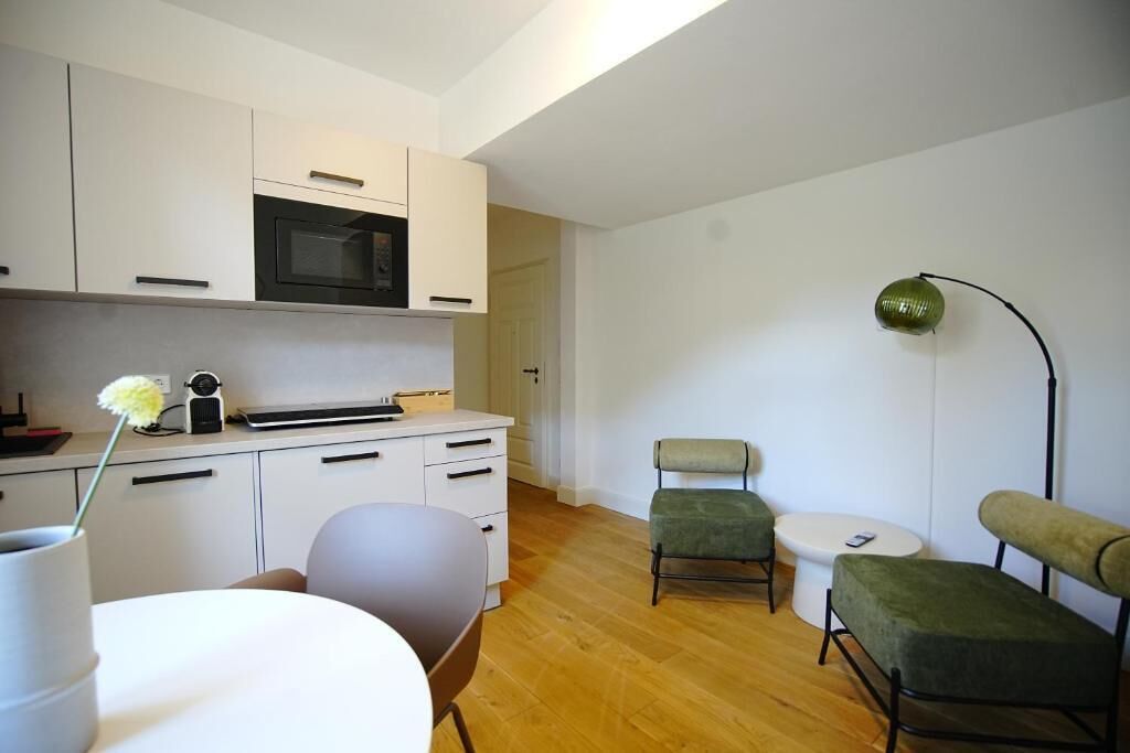 A modern kitchen with white cabinets, a microwave, and a small table with chairs.
