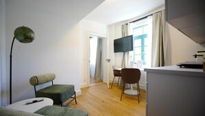 A modern living room with a sofa, a small table, a lamp, and a TV. - Königsgleis-Apartments (Bad Wildbad)