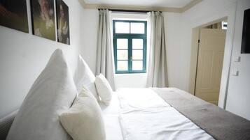 A bedroom with a bed, a window with curtains, and a door.