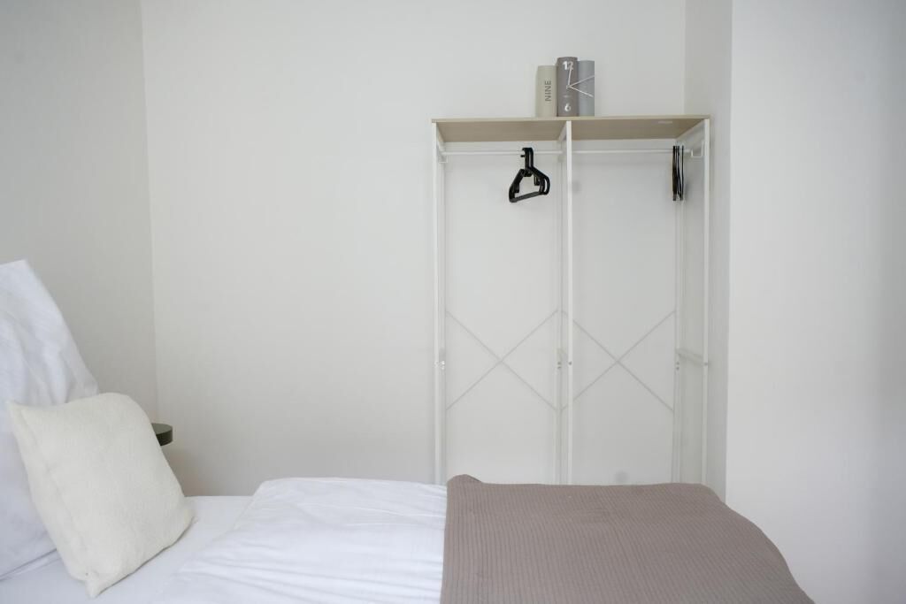 Un dormitorio con una cama, un armario blanco y una mesita de noche.