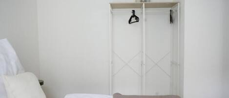 Un dormitorio con una cama, un armario blanco y una mesita de noche.